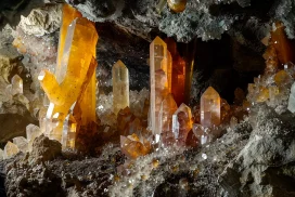 Cristales de cuarzo naranja en cueva oscura.